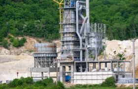 Cement plant with high metal factory structure at industrial production area.